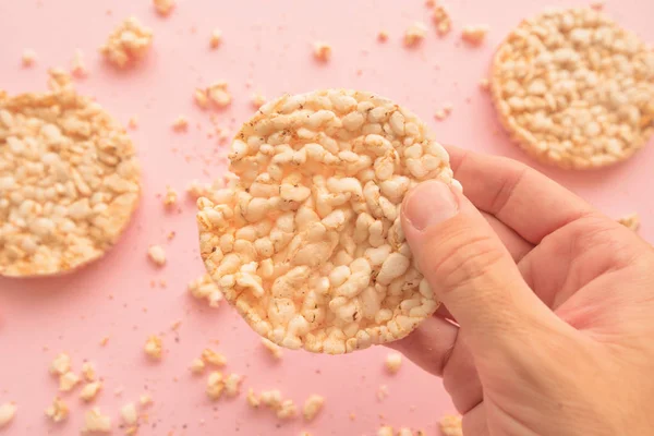 Reiskuchen Männlicher Hand Über Pastellrosa Hintergrund Overhead Ansicht — Stockfoto