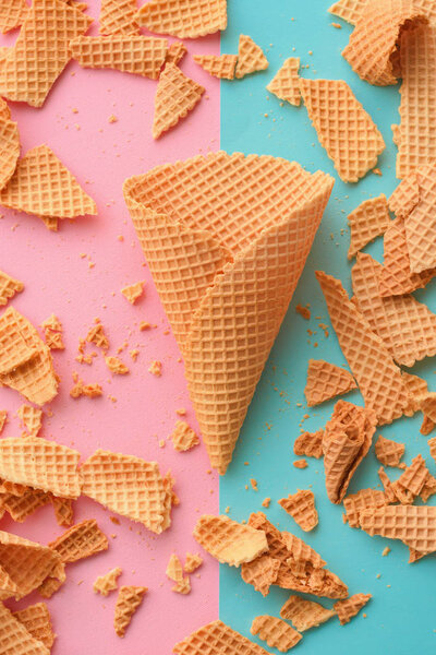 Ice cream waffle cones on pastel pink and blue background, top view flat lay modern minimal composition