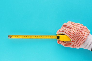 Boyutu şerit metre ile ölçme tamirci El aracıyla üzerinde mavi arka plan izole