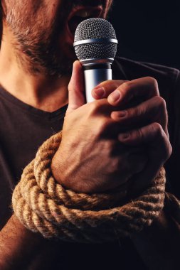 Halatlar, düşük anahtar görüntü ifade özgürlüğü, kavramsal görüntü el ile bir mikrofon tutan erkek kişi ile bağlı