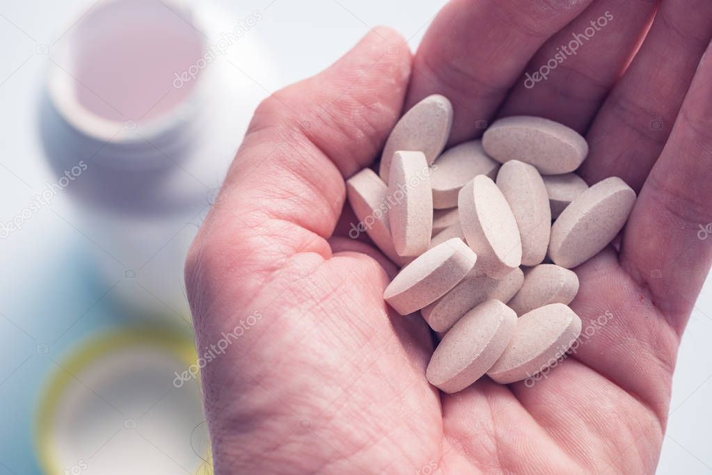 Vitamin supplement pills in hand close up with selective focus