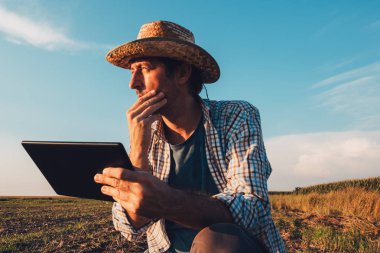 Tarımsal üretim planlama ve hazırlık modern teknoloji kullanan günbatımı, ciddi kendine güvenen adam çıplak boş alanında tablet bilgisayar ile çiftçi ziraat mühendisi