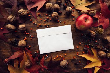 Sonbahar posta zarf düz ahşap masa kuru akçaağaç yaprakları ve mevsim meyveleri ile dekore edilmiş kadar sahte lay