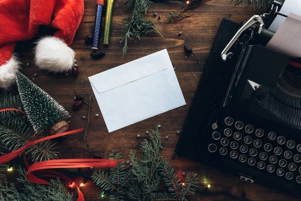 Writing a letter to Santa Claus for Christmas, blank envelope on table among festive holiday decoration