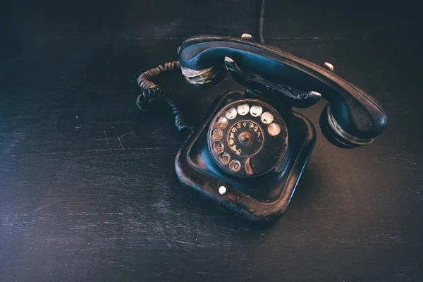 Black vintage landline telephone, old and weathered. Broken communication concept.