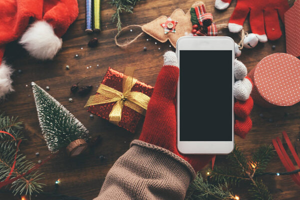 Smartphone in hand for Christmas season mock up with festive holiday decoration in background.