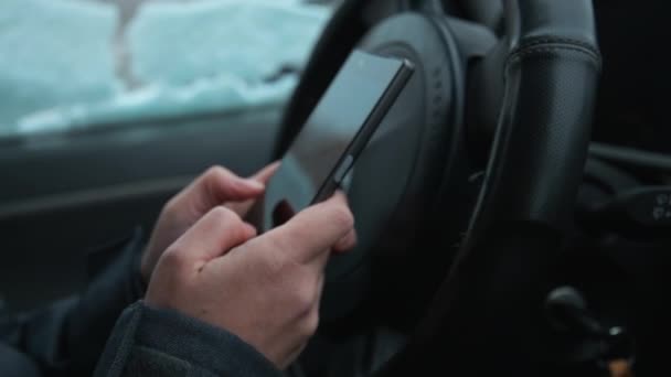 駐車中の車 外は雪が降っている中でテキスト メッセージを携帯電話 スローモーションでメッセージを入力する手のクローズ アップ — ストック動画