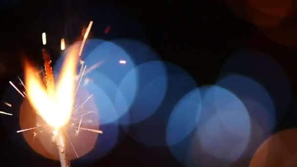 きらめく光のボケ味で飾られた暗い背景にスローモーションで燃焼お祭り休日線香花火 — ストック動画
