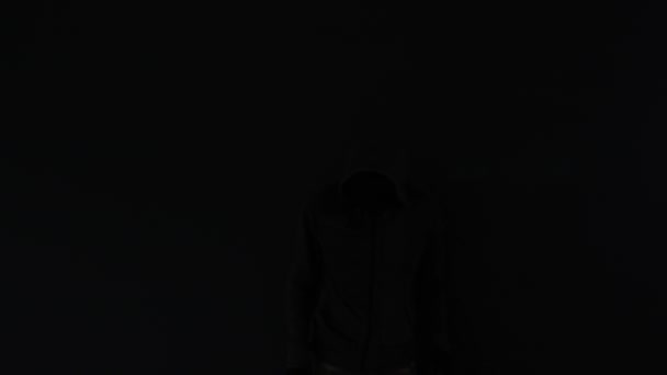 暗闇の中 低キー映像 スローモーションに逃げるフード刑事 — ストック動画