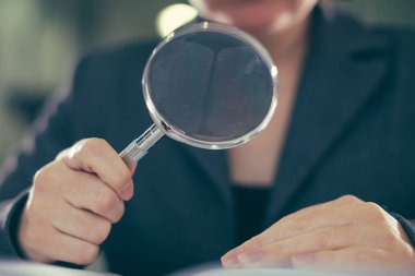 Business corruption audit inspection concept, female inspector using magnifying glass clipart