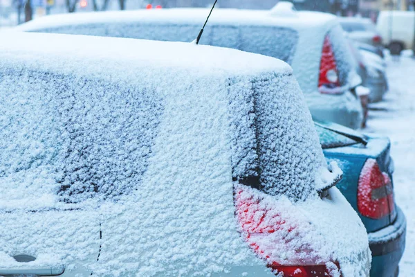 Parked cars on the street covered in snow on cold winter day