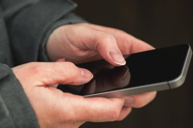 Soğuk kış gününde sokakta sms metin mesajı göndermek için mobil telefon kullanan kadın elinde kapat