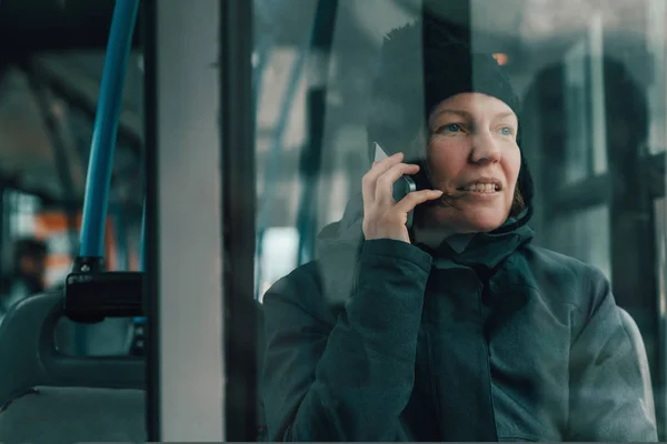 寒い冬の午後にバスで携帯電話で話している美しい大人の女性 — ストック写真