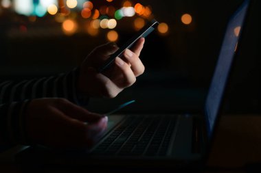 Karanlık odada, düşük anahtar görüntüleri seçici odak ile dizüstü bilgisayar kullanan online kredi kartı satın alma