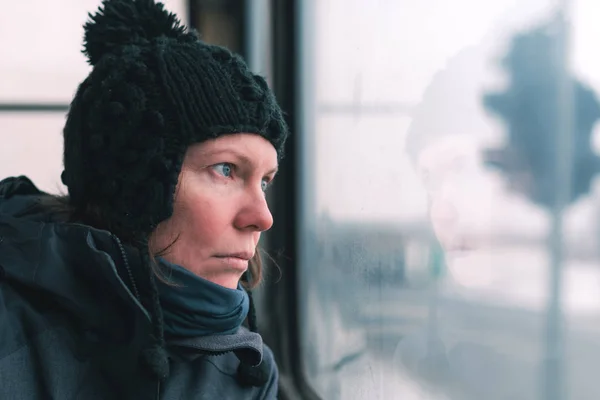寒い冬の日に通りの窓を通して見るバス上悲しい女 — ストック写真
