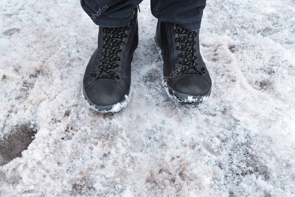 Male feet in boots standing in pure winter snow