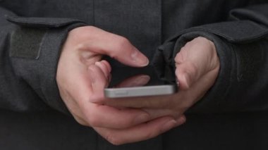 Casual erkek manifatura mesajı Caddesi üzerinde cep telefonunda, soğuk kış öğleden sonra elinde yakın çekim