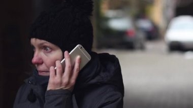 Cep telefonu Caddesi'ndeki soğuk kış gününde konuşurken endişe endişeli kadın