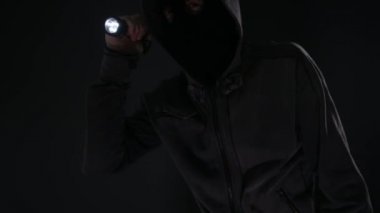 Hırsız davetsiz misafir Oda meşale ile arama ve kameraya yaklaşırken karanlık, korkutucu bir ninjaydım kukuletalı maskeli şahsen el feneri ile