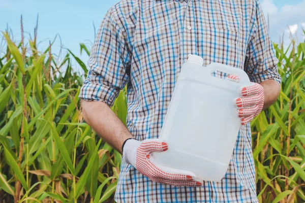 Farmer holding unlabeled pesticide jug in field, agronomist recommends hebicide for corn crop protection, mock up