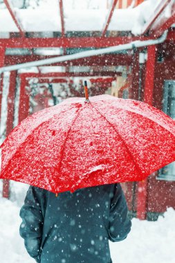 Yalnız ve üzgün kadın kentsel çevre ile kış karda yürüme kırmızı şemsiye altında