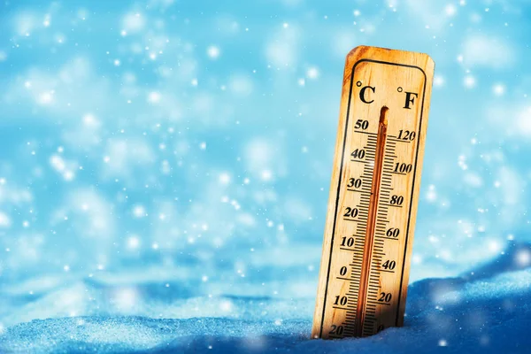 Cold temperature below zero on thermometer in snow during winter season