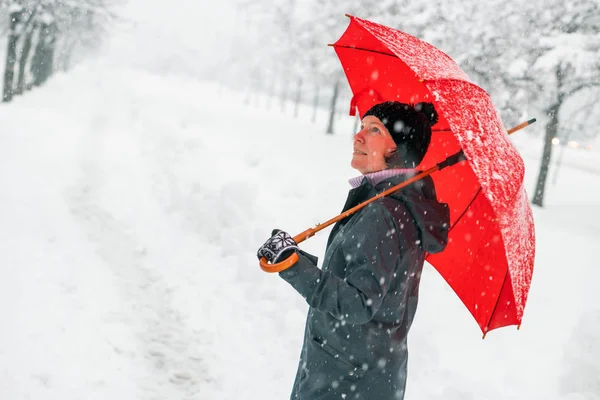公園で屋外の冬の雪を楽しんでいる赤い傘と幸せな女 — ストック写真