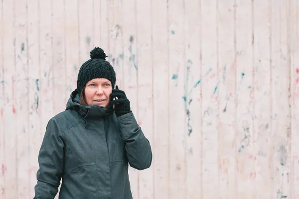 手机交谈 成年白种人妇女在寒冷的冬日在街上的智能手机上交谈 — 图库照片