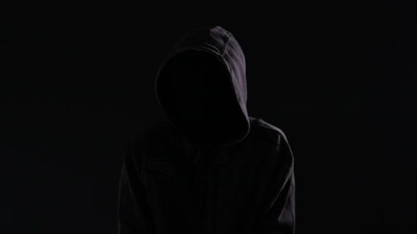 不気味なと脅迫を探してパーカーと隠されている顔が 夜に街の通りを歩いてフーリガン — ストック動画