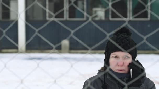 Beunruhigte Frau Telefoniert Auf Der Straße Hinter Dem Maschendrahtzaun Der — Stockvideo