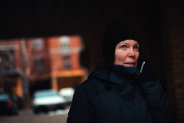 Cep telefonu Caddesi'ndeki soğuk kış gününde konuşurken endişe endişeli kadın