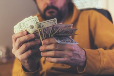 Casual adam Amerikan Doları banknot sayma, ellerin para ile yakın çekim