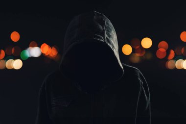 Ürkütücü ve tehdit holigan hoodie ve gizlenmiş yüz geceleri, şehrin sokaklarında yürüyüş ile