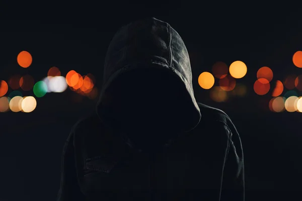 不気味なと脅迫を探してパーカーと隠されている顔が 夜に街の通りを歩いてフーリガン — ストック写真
