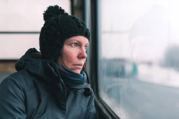 在寒冷的冬日里 公交车上的悲伤女子透过窗户望着街道 — 图库照片