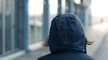 Şehir sokak soğuk kış öğleden sonra yavaş yürüyen kukuletalı kadın kişinin arka görünümü