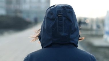 Şehir sokak soğuk kış öğleden sonra yavaş yürüyen kukuletalı kadın kişinin arka görünümü