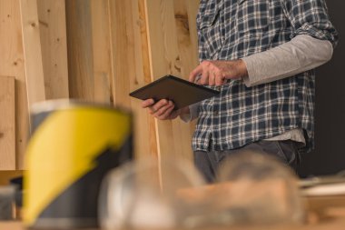 Yeni bir DIY proje planlama için küçük iş ahşap atölyesinde dijital tablet kullanarak marangoz