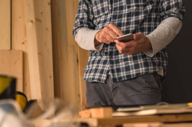 Yeni bir DIY proje planlama için küçük iş ahşap atölyesinde Smartphone kullanarak marangoz