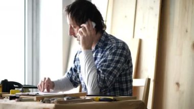 Hareket eden telefon içinde onun küçük işletme doğrama Atölyesi konuşurken erkek marangoz