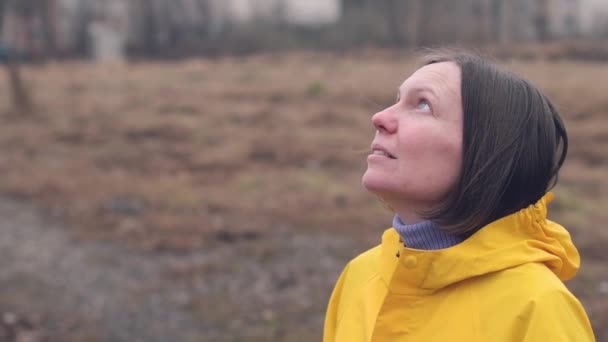 Γυναίκα Κίτρινα Αδιάβροχα Κοιτώντας Ψηλά Στο Βροχερό Σύννεφα Ενώ Σταγόνες — Αρχείο Βίντεο
