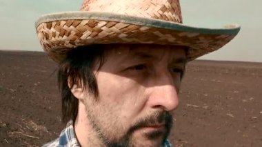 Çiftçi yürüyor ve onun sahasında seyir, ekose gömlek ve hasır şapka giyen erkek çiftlik işçisi sonraki tarımsal etkinlik, el ayak planlıyor