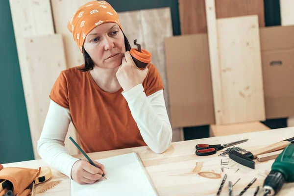 Женщина плотник пьет кофе и планирует DIY проект — стоковое фото