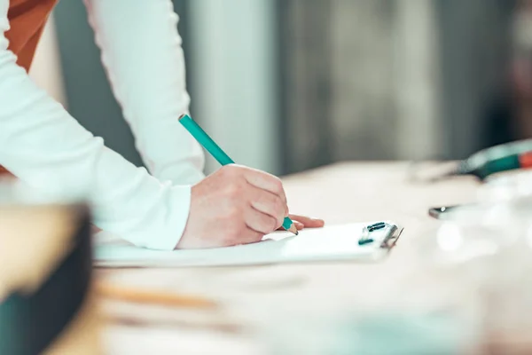 Female carpenter writing project notes in woodwork workshop — Stock Photo, Image