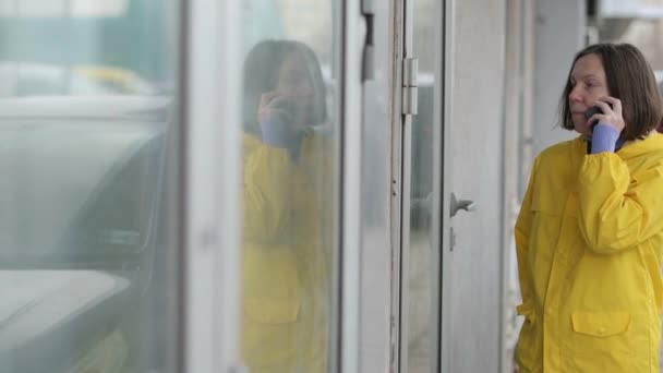 Γυναίκα Κίτρινα Αδιάβροχα Μιλώντας Κινητό Τηλέφωνο Δυσπιστία Έξω Στο Δρόμο — Αρχείο Βίντεο