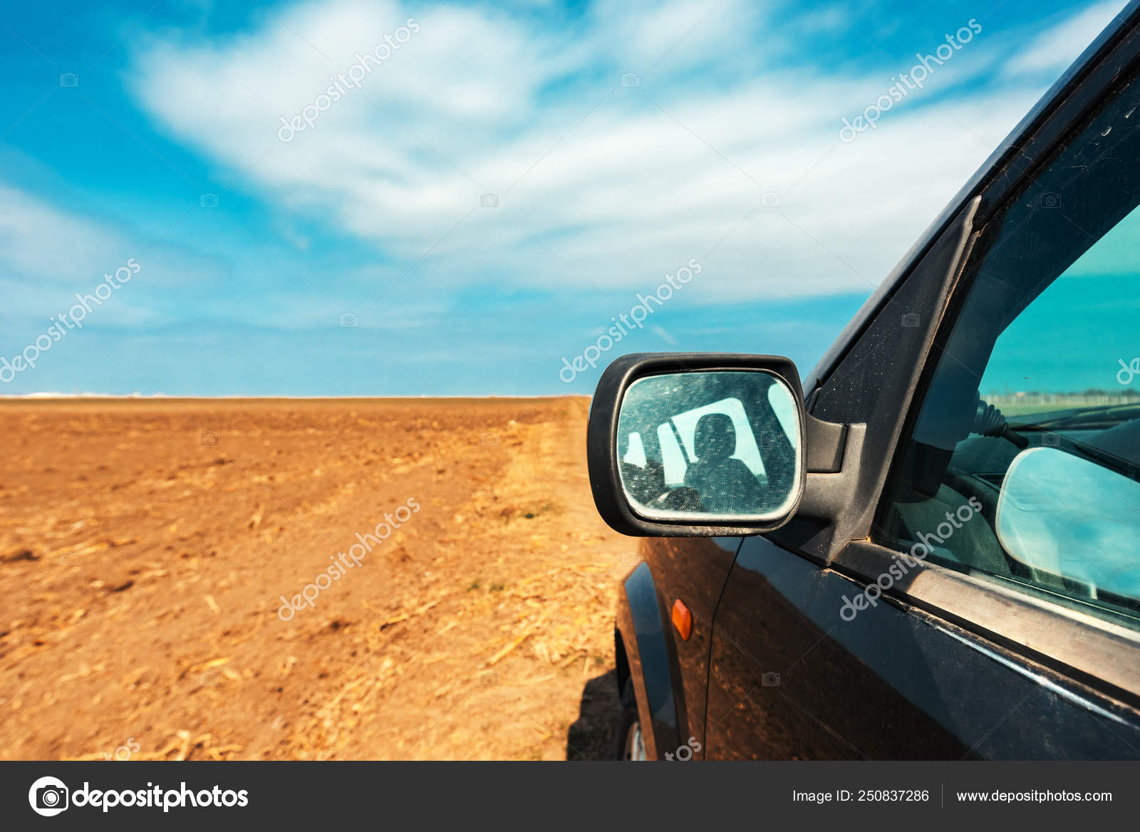 Wing mirror of a car on dirt country road Stock Photo by