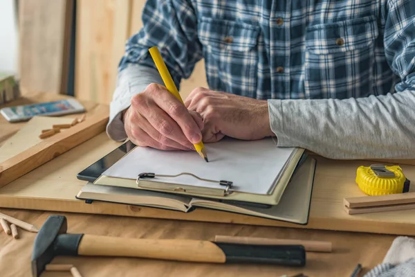 Carpintero escribir notas del proyecto portapapeles y hacer lista — Foto de Stock