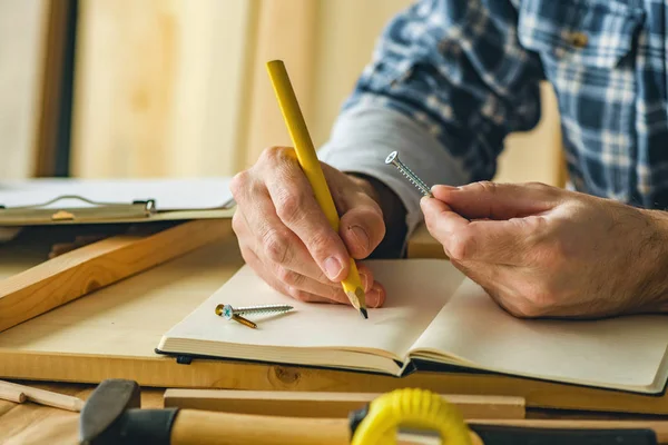 Carpintero escribiendo notas del proyecto — Foto de Stock