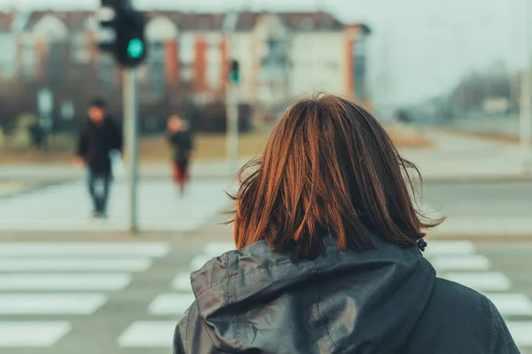 Rückansicht einer Frau auf dem Fußgängerüberweg in der Stadtstraße — Stockfoto