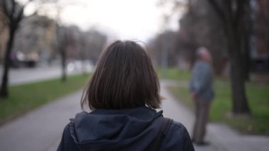 Casual yetişkin Kafkas kadın şehrin bulutlu bahar öğleden sonra ağır çekim el görüntüleri sokak aşağı yürüyüş görünümünü arka